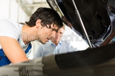 man and car mechanic looking beneath a hood