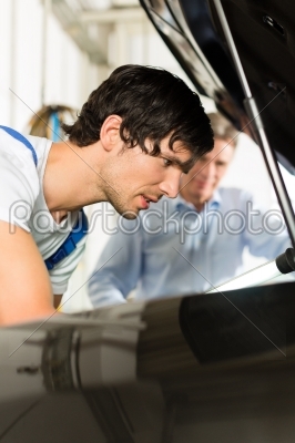 man and car mechanic looking beneath a hood