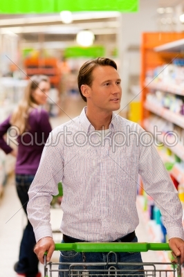 Man and woman in supermarket with shopping cart