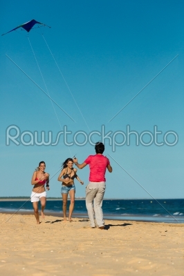 Man and women running on beach with kite