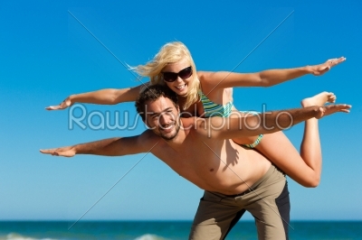 Man carrying his wife on beach in vacation