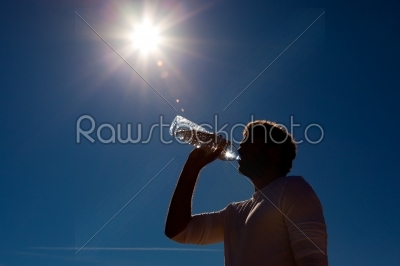 Man drinking bottled water under sun