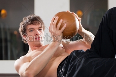 Man is exercising with medicine ball in gym