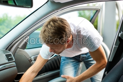Man is hoovering or cleaning the car