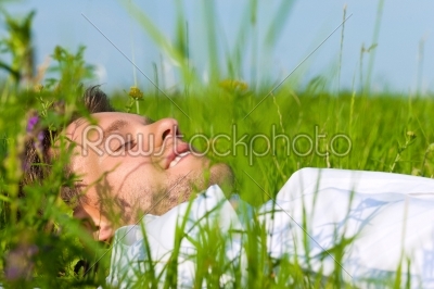 Man laying on a lawn and is dreaming