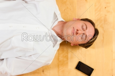 Man lying on the floor beside mobile phone