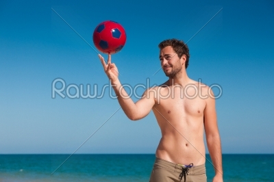 Man on beach balancing soccer ball