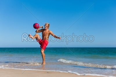 Man on beach playing soccer