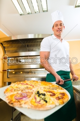 Man pushing the finished pizza from the oven