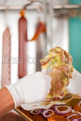 Man working in butchers shop showing meat