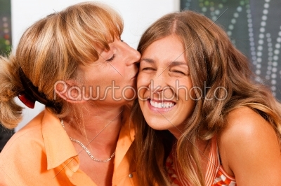 Mother is kissing her daughter as a sign of love