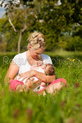 Mother nursing baby on meadow