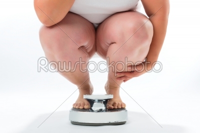 Obese young woman crouching on a scale