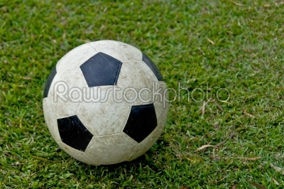 Old soccer ball on green grass