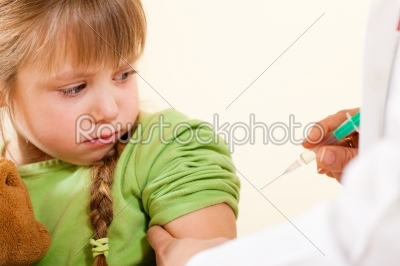 Pediatrician doctor applying syringe to child 