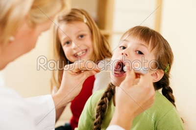 Pediatrician doctor examining throat of girl
