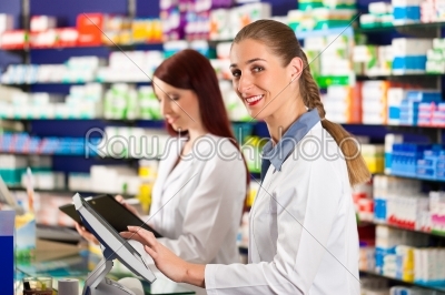 Pharmacist with assistant in pharmacy