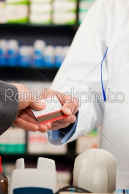Pharmacist with paying customer in pharmacy