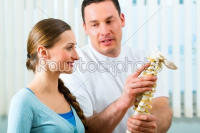 Physiotherapist in his practice, he explains a female patient the vertebral column and the emergence of back pain