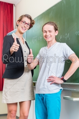 School class Teacher and student stand in front of a blackboard with math work in a classroom during lesson