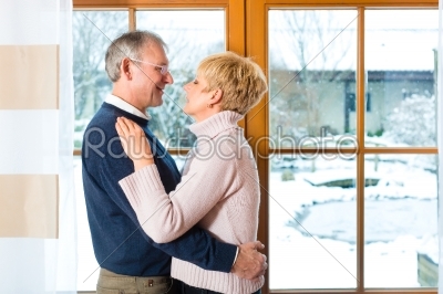 Senior couple looking or of the window hugging