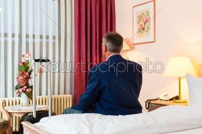 Senior man sitting on the bed in the hotel room