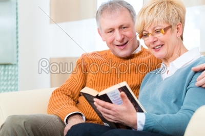Seniors at home reading a book together 