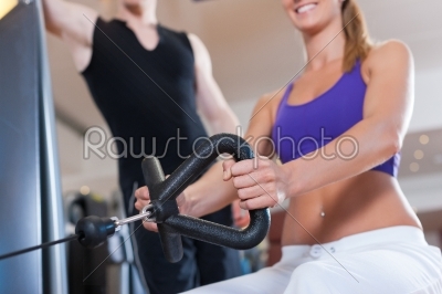 Sport - couple is exercising on machines in gym