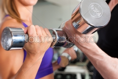 Sport - couple is exercising with barbell in gym