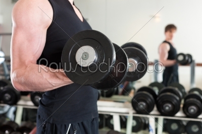 Sport - man is exercising with barbell in gym