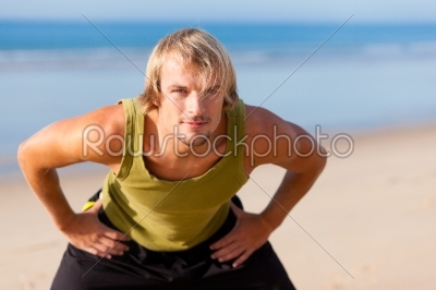 Sportive man doing gymnastics on the beach