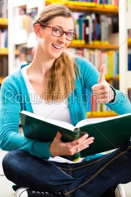 Student with pile of books learning in library