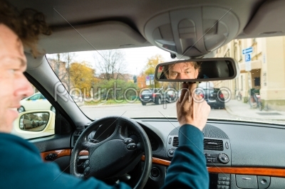 Taxi driver is looking in the driving mirror