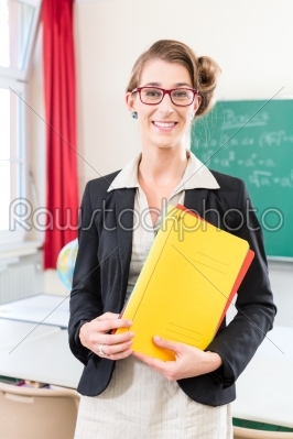 Teacher holding folder in school in front of a class