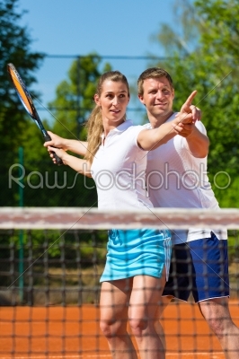 Tennis teacher helping woman to play