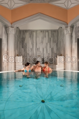 Three friends in swimming pool or thermal bath