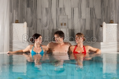 Three friends in swimming pool or thermal bath