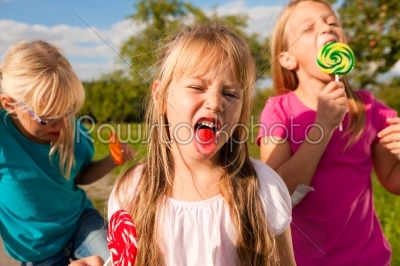 Three girls eating lollypops