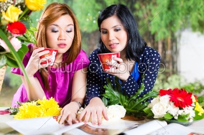 Two Asian girlfriends with fashion magazine