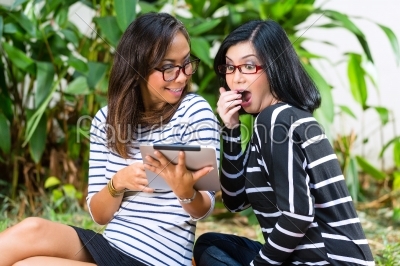 Two Asian girlfriends with tablet computer