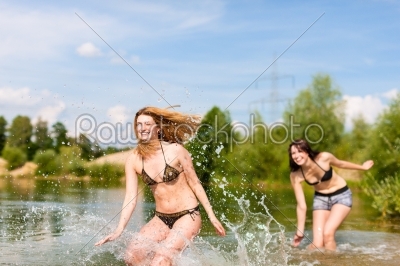 Two happy women having fun at lake in summer