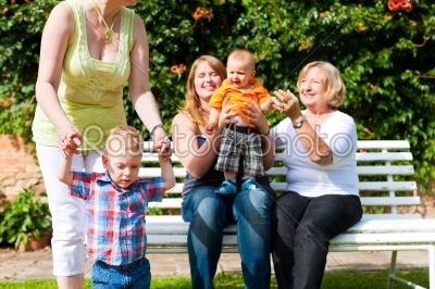 Two mothers with grandmother and children in park