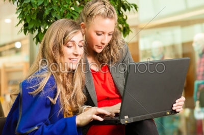 Two women shopping in mall with laptop