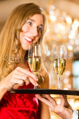 Waiter serves champagne glasses on tray in restaurant