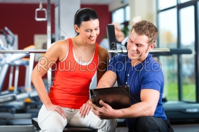 woman and Personal Trainer in fitness gym