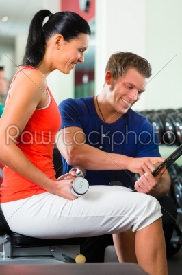 woman and Personal Trainer in gym, with dumbbells
