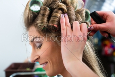 Woman at the hairdresser curling hair