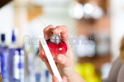 woman buying perfume in shop or store