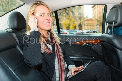Woman driving in taxi, she is on the phone