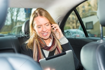 Woman driving in taxi, she is on the phone